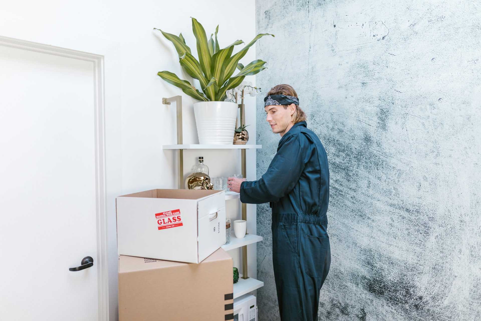 Man in uniform arranging home items with cardboard boxes ready for moving.